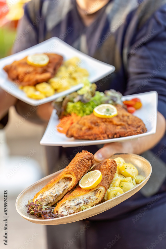 A waitress serving freshly prepared Cordon Bleu in different variations, view from above