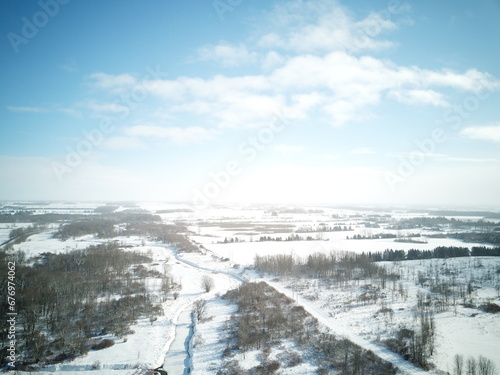 Aerial view of a snowy forest with a bright sky background