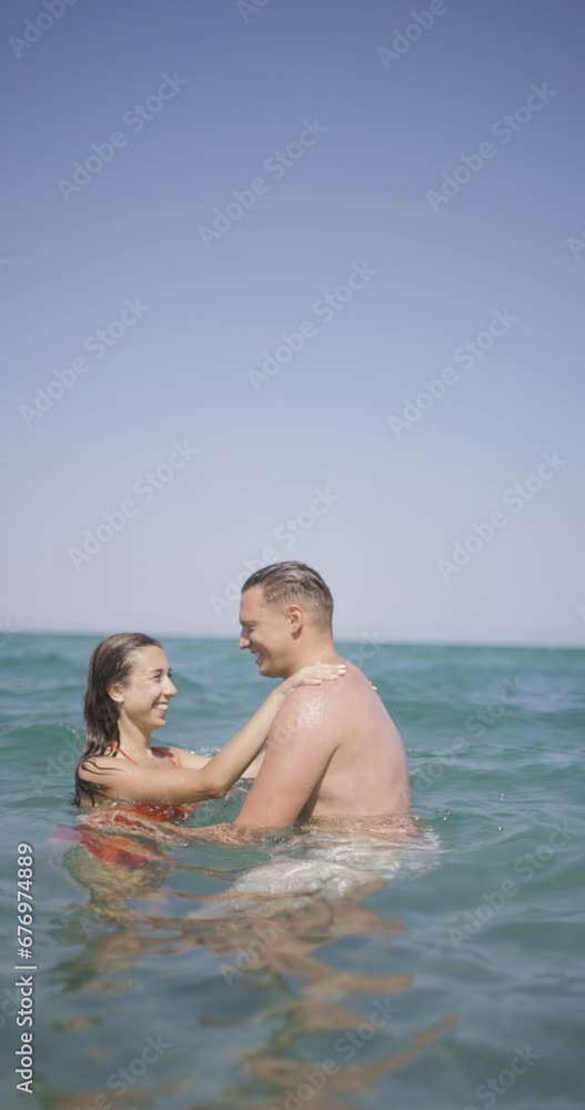 Couple having good time at sea. Boyfriend and girlfriend hugging in the water. Summer fun concept. Vertical video recorded on cinema camera at 120fps. Couple having good time at sea. Boyfriend and girlfriend hugging in the water. Summer fun concept. Vertical video recorded on cinema camera at 120fps.
