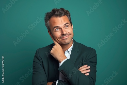 Thoughtful businessman looking at camera, smiling, one color background, generative ai © Nia™