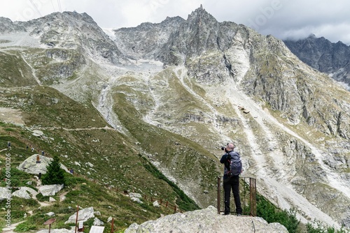 Man with a backpack standing on an observation deck and photographing a mountain range, Mont Blanc