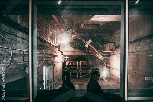 Feet on the glass floor of the elevator of indutrial building photo