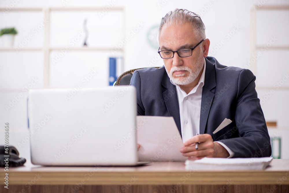 Old male employee working in the office Old male employee working in the office