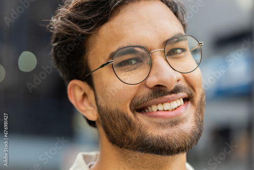Portrait of happy young Indian man face smiling friendly, glad expression looking at camera dreaming, resting relaxation feel satisfied good news outdoors. Arabian Hindu guy in street. Business people