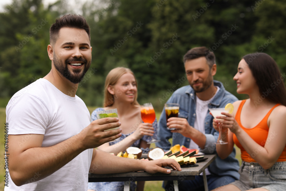 Friends having cocktail party outdoors. Happy man with glass of drink, selective focus Friends having cocktail party outdoors. Happy man with glass of drink, selective focus