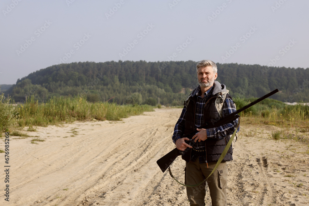 Man with hunting rifle outdoors. Space for text Man with hunting rifle outdoors. Space for text