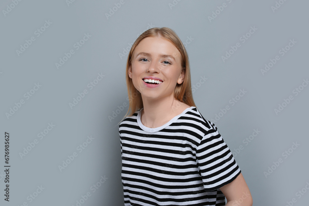 Portrait of beautiful young woman in striped t-shirt on grey background Portrait of beautiful young woman in striped t-shirt on grey background
