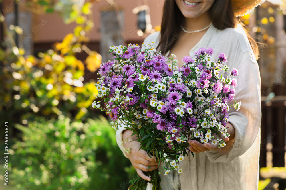Woman holding bouquet of beautiful wild flowers outdoors, closeup. Space for text