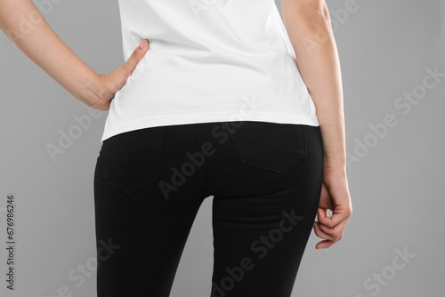 Woman wearing stylish black jeans on light gray background, closeup