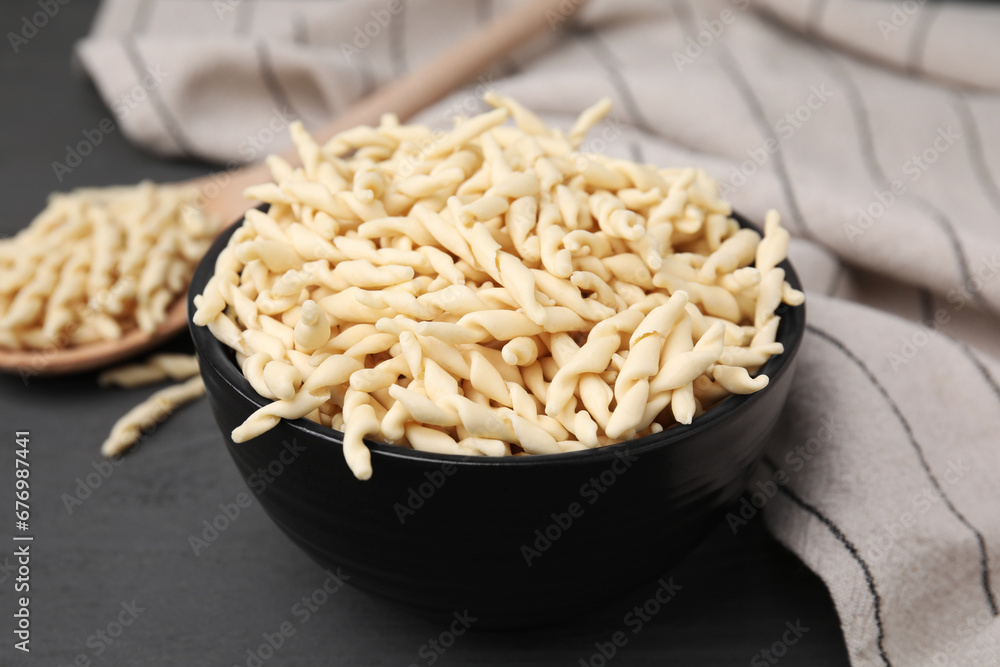Uncooked trofie pasta in bowl on grey table, closeup Uncooked trofie pasta in bowl on grey table, closeup