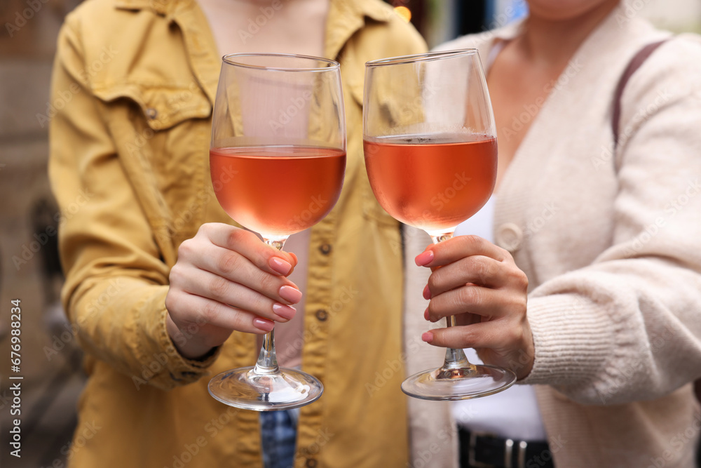 Women clinking glasses with rose wine outdoors, closeup Women clinking glasses with rose wine outdoors, closeup