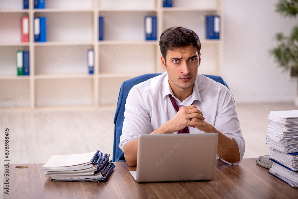 Young male employee and too much work in the office Young male employee and too much work in the office
