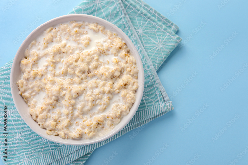 Tasty boiled oatmeal in bowl on light blue table, top view. Space for text Tasty boiled oatmeal in bowl on light blue table, top view. Space for text