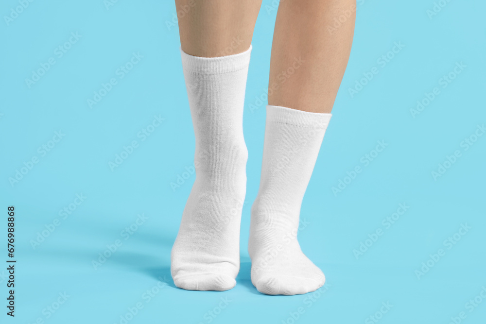 Woman in stylish white socks on light blue background, closeup Woman in stylish white socks on light blue background, closeup