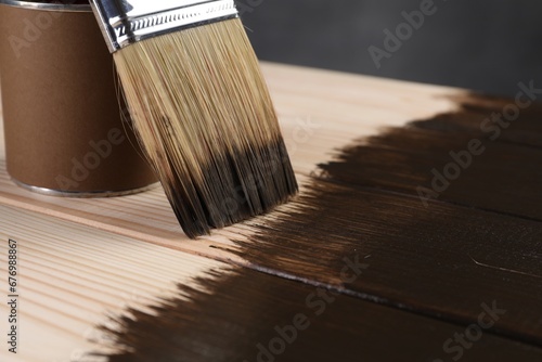 Applying wood stain with brush onto wooden surface, closeup. Space for text
