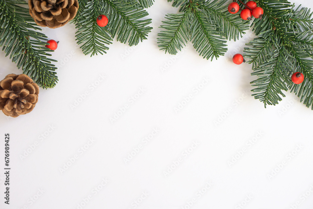 Christmas background. Green branches with red berries and brown cones.