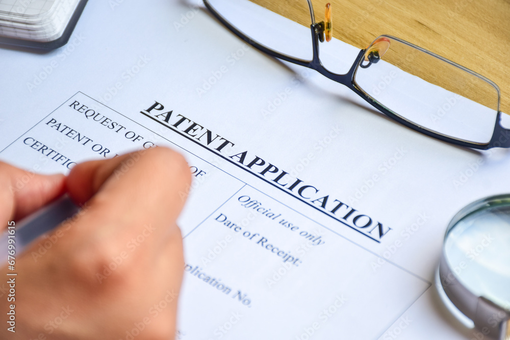 Woman filling out Patent Application form to publish invention. Close-up view, selective focus. Woman filling out Patent Application form to publish invention. Close-up view, selective focus.