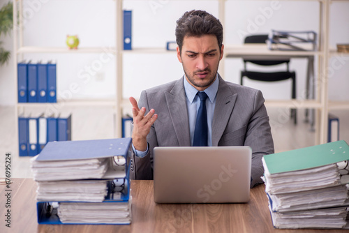 Young male employee and too much work in the office