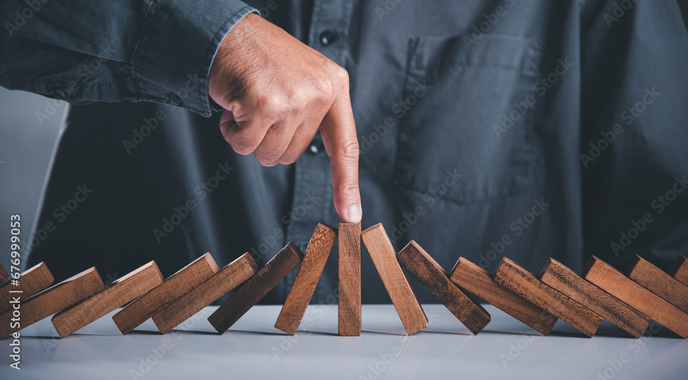 © sorapop - Close up hand stopping or preventing falling block in line with risk project control, Finger of businessman pointing one wooden to stopping domino effect stopped, Risk protection concept © sorapop - Close up hand stopping or preventing falling block in line with risk project control, Finger of businessman pointing one wooden to stopping domino effect stopped, Risk protection concept