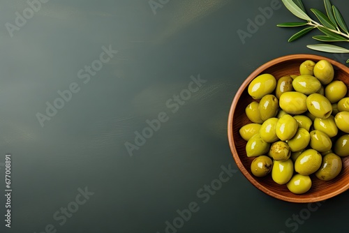 Top down perspective of a wooden bowl filled with green olives and room for adding text