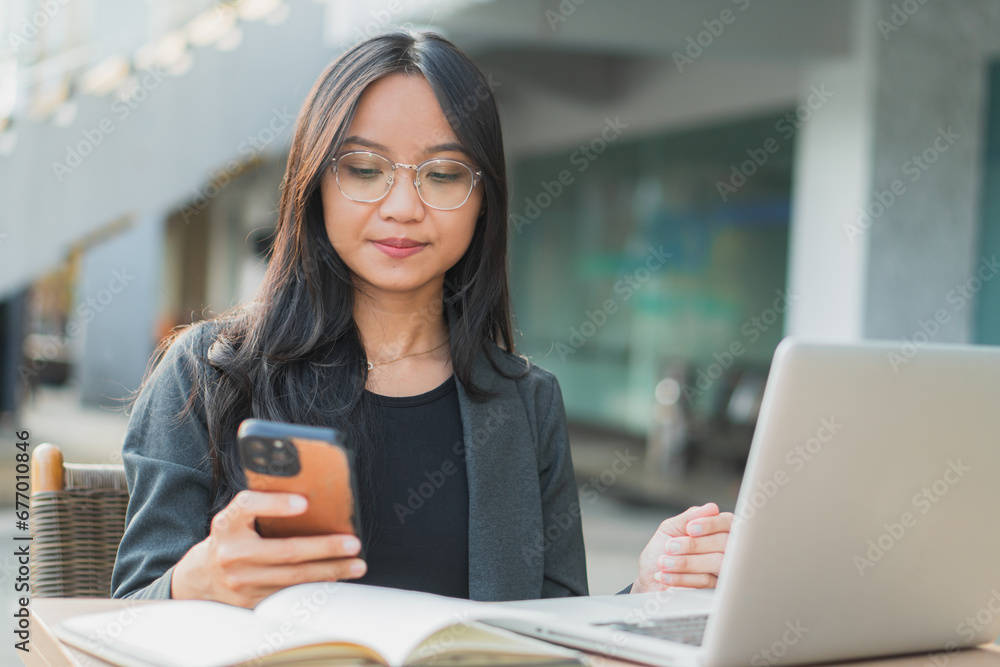 Young confident businesswoman using her smart phone while sitting at the office desk. Young confident businesswoman using her smart phone while sitting at the office desk.