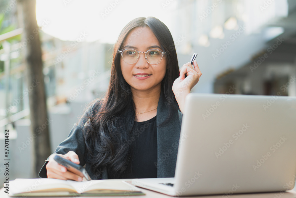 Young confident businesswoman using her smart phone while sitting at the office desk. Young confident businesswoman using her smart phone while sitting at the office desk.