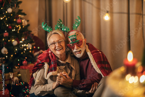 Portrait of a affectionate senior couple sitting at home on Christmas eve and hugging.
