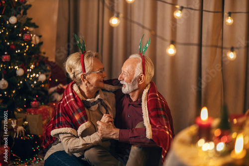A happy festive senior couple celebrating New Year and Christmas at home, hugging and bonding.