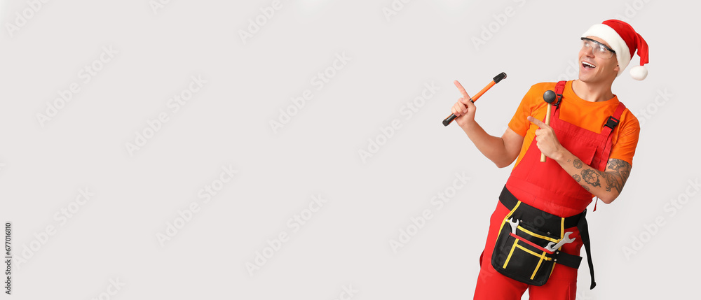 Worker in Santa hat and with tools on light background with space for text Worker in Santa hat and with tools on light background with space for text