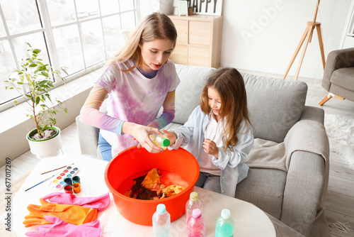 Εκτύπωση καμβά Young woman and little girl tie-dyeing fabric together at home, creative DIY cra