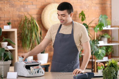 Male cashier using cash cou...