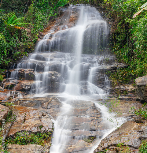 beautiful cascading waterfall over rocks long exposure in Chiangmai Chiang mai mountains northern thailand amongst lush green tropical rainforest