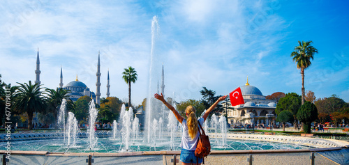 Happy woman tourist with turkish flag enjoys Istanbul city- Blue mosque, Hagia Sophia mosque, fountain and palm tree in Turkey photo