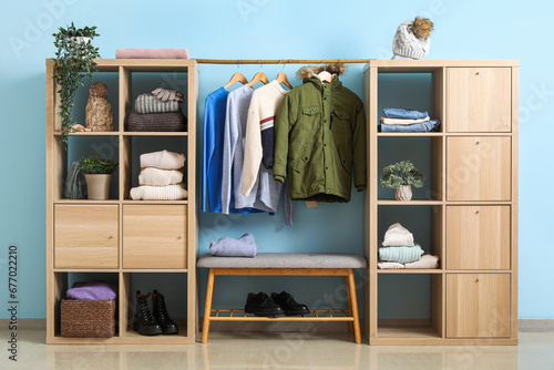 Wardrobe with winter clothes near blue wall