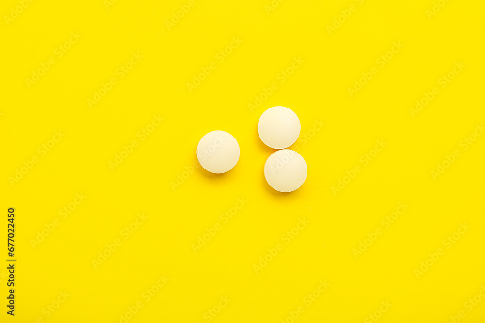 White medical pills on yellow background White medical pills on yellow background