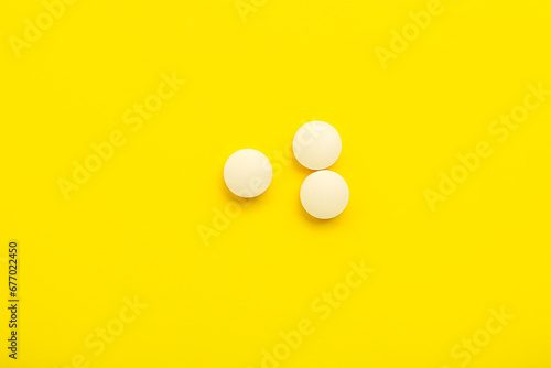 White medical pills on yellow background