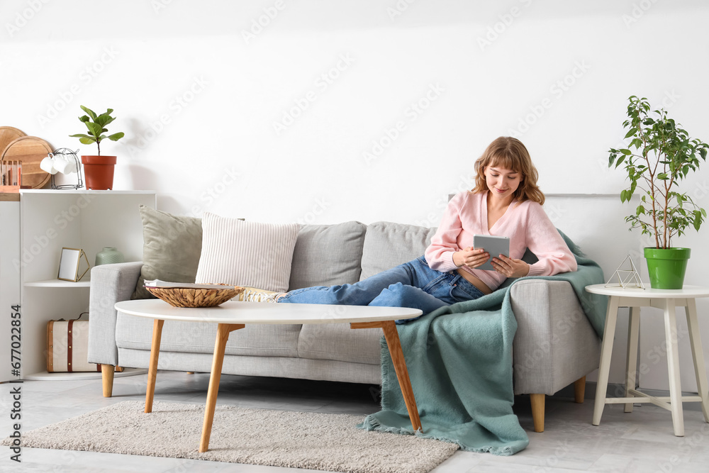 Young woman with tablet computer relaxing on sofa at home Young woman with tablet computer relaxing on sofa at home