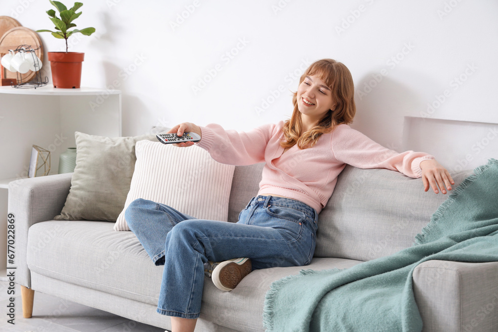 Obraz premium Young woman watching TV on sofa at home