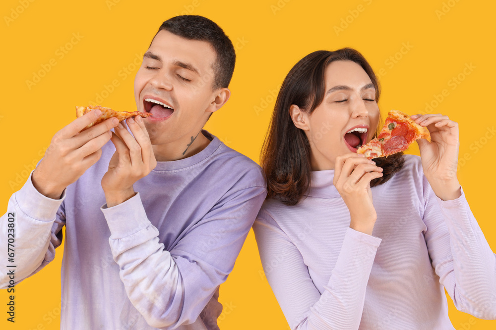 Young couple eating tasty pepperoni pizza on color background Young couple eating tasty pepperoni pizza on color background