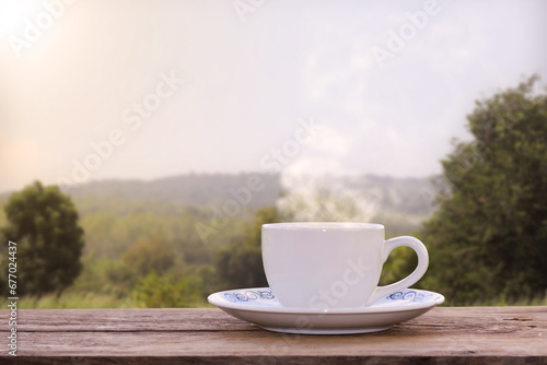 Cup of hot coffee on a wooden table, natural scenery backdrop, river sky and mountain views