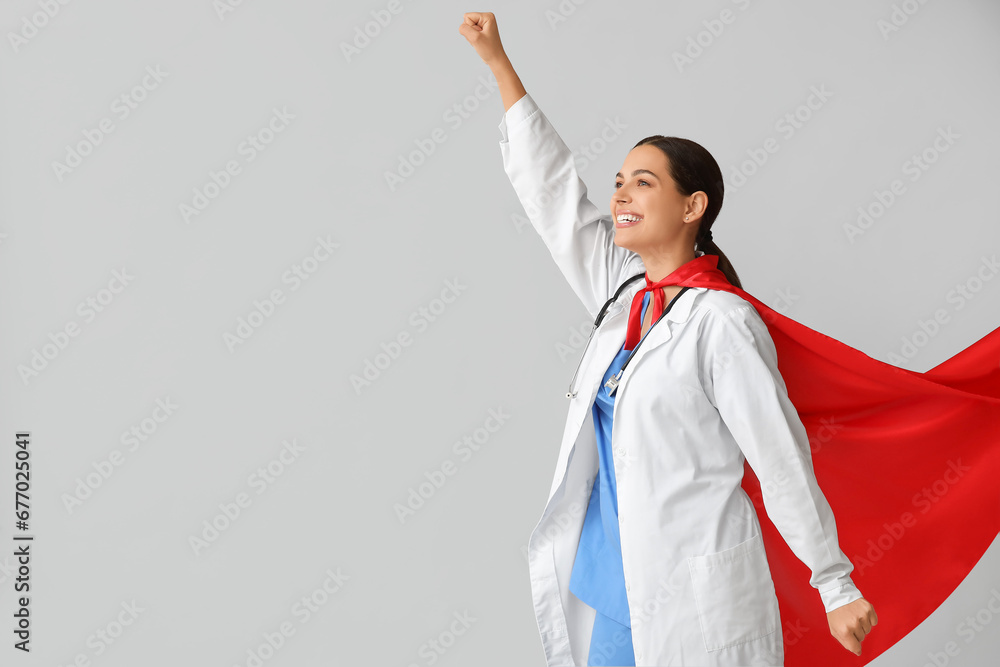 Beautiful female doctor dressed as super hero on white background - obrazy, fototapety, plakaty 