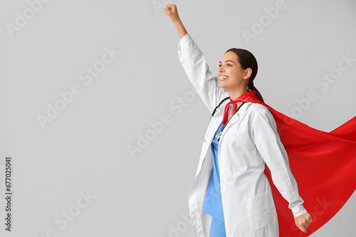 Beautiful female doctor dressed as super hero on white background photo