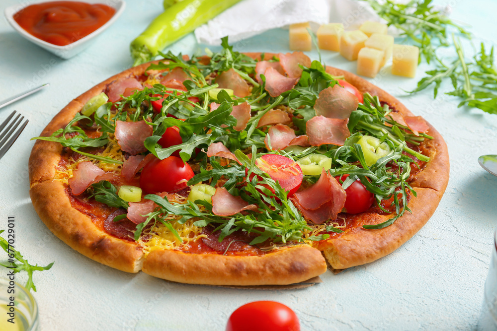 Delicious pizza with tomatoes and arugula on light blue background
