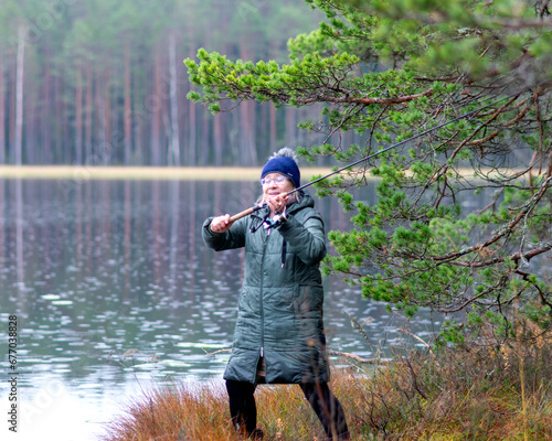 fisherwoman on the shore of a swamp lake, forest and swamp vegetation, rainy and cloudy day
