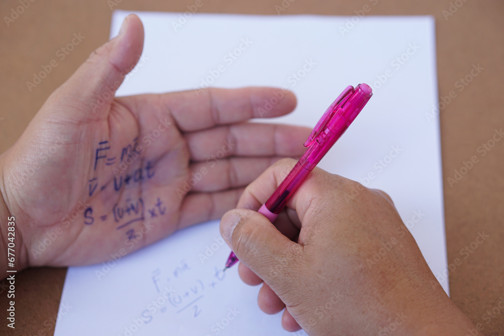 Palm with written physics formula on it during doing writing examination on paper by pen. Concept, cheat the test, Dishonest behaviour. Education assessment. Palm with written physics formula on it during doing writing examination on paper by pen. Concept, cheat the test, Dishonest behaviour. Education assessment.