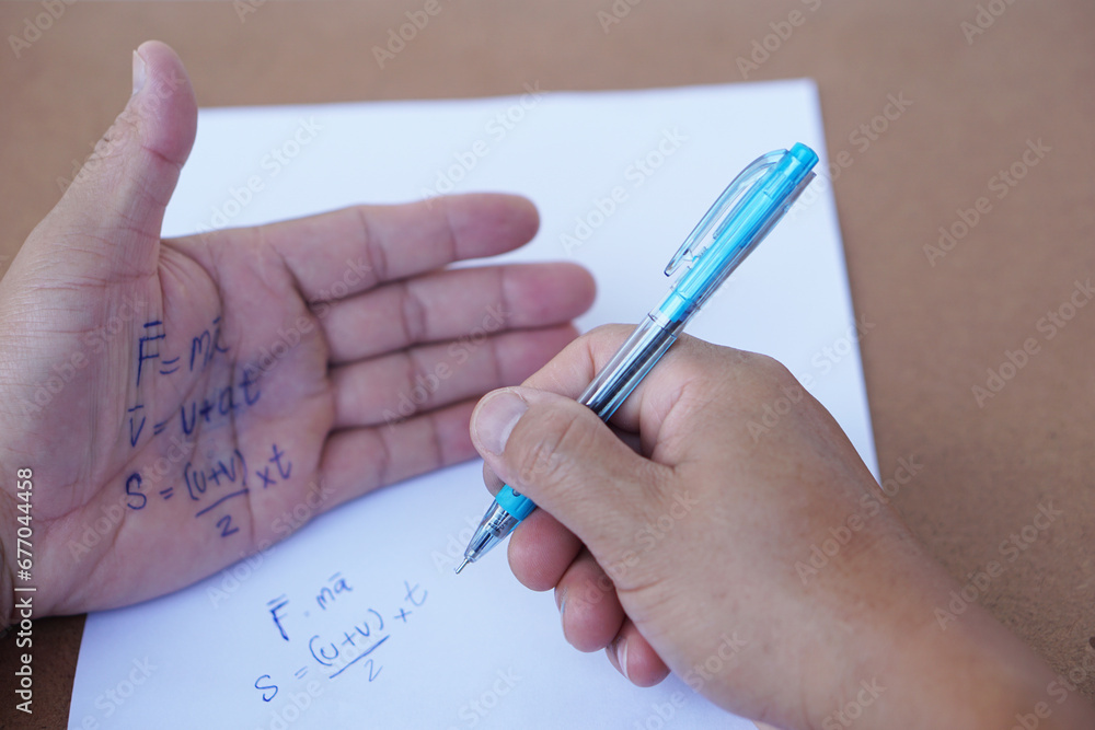 Palm with written physics formula on it during doing writing examination on paper by pen. Concept, cheat the test, Dishonest behaviour. Education assessment. Palm with written physics formula on it during doing writing examination on paper by pen. Concept, cheat the test, Dishonest behaviour. Education assessment.