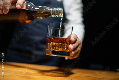 Barman pouring whiskey whiskey glass..