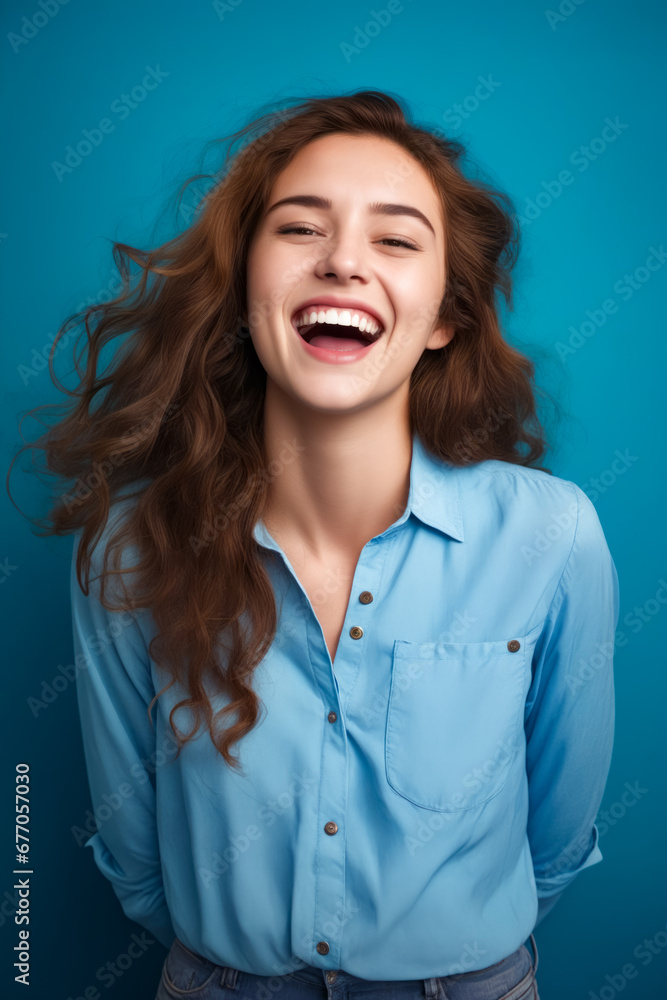 Woman laughing and wearing blue shirt with her hair blowing in the wind.