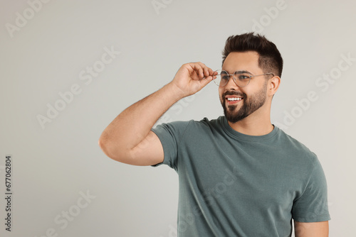 Handsome man wearing glasses on light gray background, space for text © New Africa