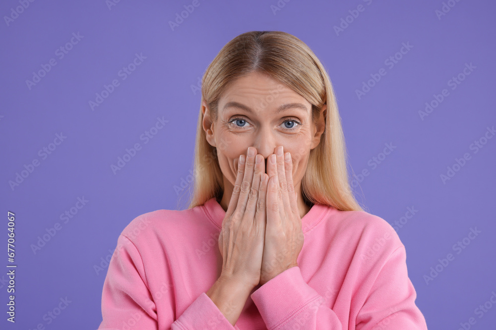 Portrait of embarrassed woman covering mouth with hands on purple background Portrait of embarrassed woman covering mouth with hands on purple background